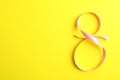 8 March, International Women`s Day. Figure eight of pink ribbon on yellow background Royalty Free Stock Photo