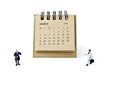 March. Calendar sheet and miniature plastic businessmen on white