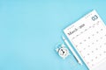 March 2024, Monthly desk calendar for 2024 year and alarm clock with paper clips on blue color background Royalty Free Stock Photo