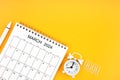 March 2024, Monthly desk calendar for 2024 year and alarm clock with paper clips on yellow color background Royalty Free Stock Photo
