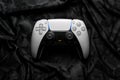 March 4, 2023, Odessa, Ukraine. White new Playstation 5 gamepad dualsense on a dark camouflage back. Cybersport poster concept