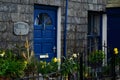 A colorful blue door with yellow flowers in front in the town of Port Isaac, Cornwall, England.