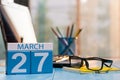 March 27th. Day 27 of month, calendar on business office background, workplace with laptop and glasses. Spring time