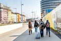 Group of young tourist couples with travel bags walking through the city street