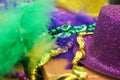 Mardi Gras background in green and shades of purple and gold with feathers and sparkly hat and beads - selective focus Royalty Free Stock Photo
