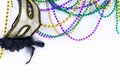 Mardi Gras beads in green, gold and purple hanging, draped in front of a white background