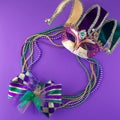 Mardi Gras beads and mask making a frame with copy space on a purple background