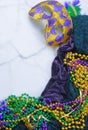 Mardis Gras border on marble background includes harlequin mask with green, gold and purple beads and matching fabrics. Royalty Free Stock Photo