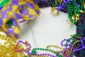 Mardis Gras border on marble background includes harlequin mask with green, gold and purple beads and matching fabrics.