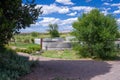 A Marfa, Texas backyard with metal rain containers, windmill, trees, and cloudy blue sky. Royalty Free Stock Photo