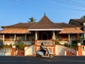 A man rides a two wheeler scooter past an old traditional house in Goa Royalty Free Stock Photo