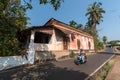 A woman rides a bike past an old Portuguese era house in Goa