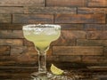 Margarita drink in a glass with a lime and a salted rim on a rustic wood background