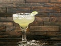 Margarita beverage in a glass with a salted rim and a lime garnish on a rustic wood background Royalty Free Stock Photo