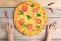 Kids hands hold cheese margarita pizza with tomatoes and basil, vegan meal on wooden rustic table,top view