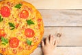 Kids hands hold cheese pizza with tomatoes and basil, vegan meal on wooden rustic table,top view