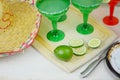 Margaritas in red and green glasses with salted rims and lime garnishes