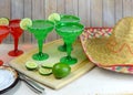 Margaritas in red and green glasses with salted rims and lime garnishes