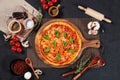 Margherita Pizza with raw cherry tomato, black pepper, garlic, and mushroom isolated on wooden cutting board on dark background Royalty Free Stock Photo