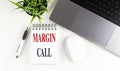 MARGIN CALL text on notebook with laptop, mouse and pen