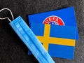 Mari El, Russia - June 12, 2021: UEFA logo and Sweden, Swedish flag is near a blue mask on the dark gray background. Tourist trip