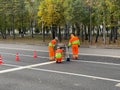Mari El, Russia - September 13, 2021: Three road workers make markings on the asphalt, the form is orange and light