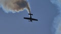 Black silhouette of an aerobatic plane descending vertically with smoke