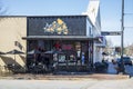 The Marietta Pizza Company with a red neon open sign, tables and chairs on the red brick sidewalk and blue sky in Marietta Georgia