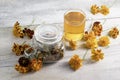 Marigold herbal tea in a glass cup, fresh and dried flowers on a white wooden table.Folk medicine. Royalty Free Stock Photo