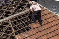 Top view of a worker removing tiles from a house to renovate the roof