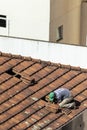 Top view of a worker removing tiles from a house to renovate the roof