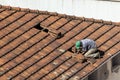 Top view of a worker removing tiles from a house to renovate the roof of a commercial poin