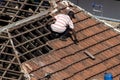 Top view of a worker removing tiles from a house to renovate