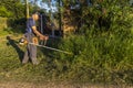 Worker, with a manual gasoline brush cutter, cuts the weeds that grew with the rains