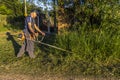 Worker, with a manual gasoline brush cutter, cuts the weeds that grew with the rains in front of the gate