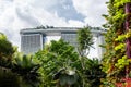 Marina Bay Sands luxury famous hotel seen through tropical plants and trees frame from Gardens by the Bay park, Singapore