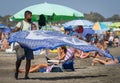 Bangladeshi veil merchant wears a medical mask on a beach among crowds of unmasked people in Marina di San Nicola, Italy