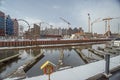 Old harbour canal with marina in ice and snow during winter in Old Town of Gdansk Poland. Ruins and granaries in the background.