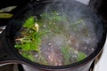 Cooking marinade at home from a variety of fresh herbs in a small saucepan