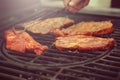 marinaded meat is grilled on a hot cast-iron grate by a cook with pliers at a barbecue party