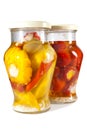 Marinaded tomatoes, stuffed and bush pumpkins and vegetable marrows in glass jar on a white background