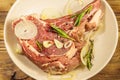 Marinated beef rib eye steak on bone with spices, onion and rosemary on wooden table Royalty Free Stock Photo