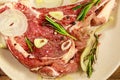 Marinated beef rib eye steak on bone with spices, onion and rosemary on wooden table Royalty Free Stock Photo