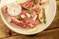 Marinated beef rib eye steak on bone with spices, onion and rosemary on wooden table Royalty Free Stock Photo