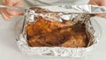 Marinated chicken meat in a glass baking pan. Chef wraps meat with aluminum foil