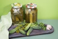 Marinated cucumbers in jars. Fresh cucumbers on a wooden cutting Board with garlic and herbs.