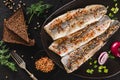 Marinated fillet mackerel or fillet herring fish with spices, greens and slice of bread on plate over dark stone background Royalty Free Stock Photo