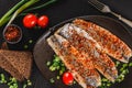 Marinated fillet mackerel or fillet herring fish with spices, greens and slice of bread on plate over dark stone background Royalty Free Stock Photo
