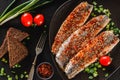 Marinated fillet mackerel or fillet herring fish with spices, greens and slice of bread on plate over dark stone background. Royalty Free Stock Photo