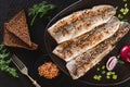 Marinated fillet mackerel or fillet herring fish with spices, greens and slice of bread on plate over dark stone background. Royalty Free Stock Photo